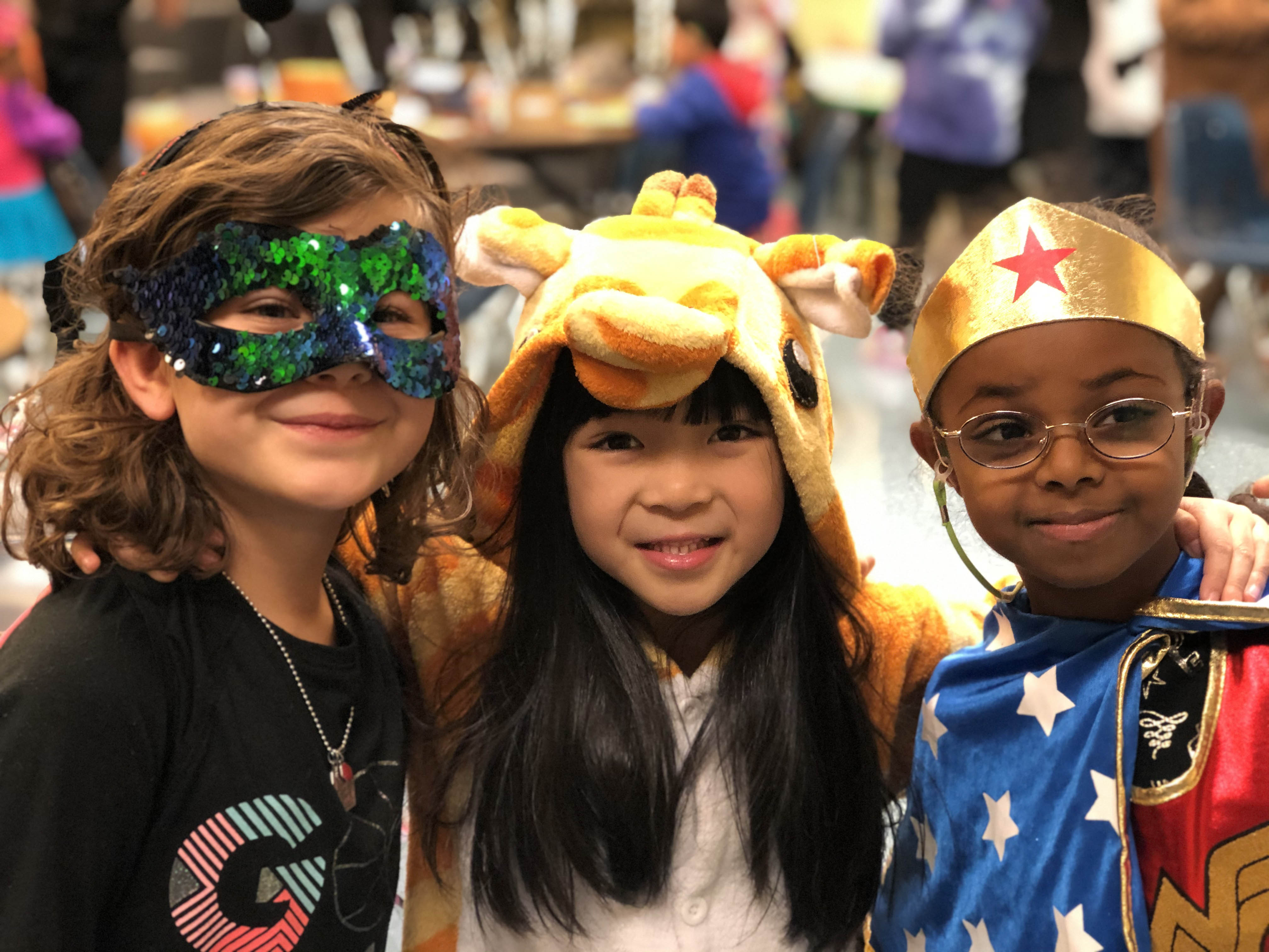 three students in their halloween costumes - sequoin mask, giraffe and wonder woman