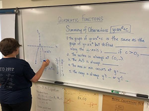 A senior years student does math on a whiteboard